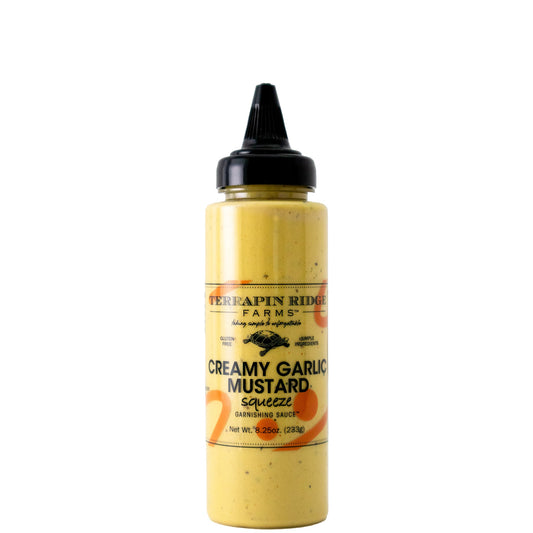 A yellow squeeze bottle with a black pointed cap and a Terrapin Ridge Farms label reading Creamy Garlic Mustard squeeze garnishing sauce, net wt. 8.25 oz.