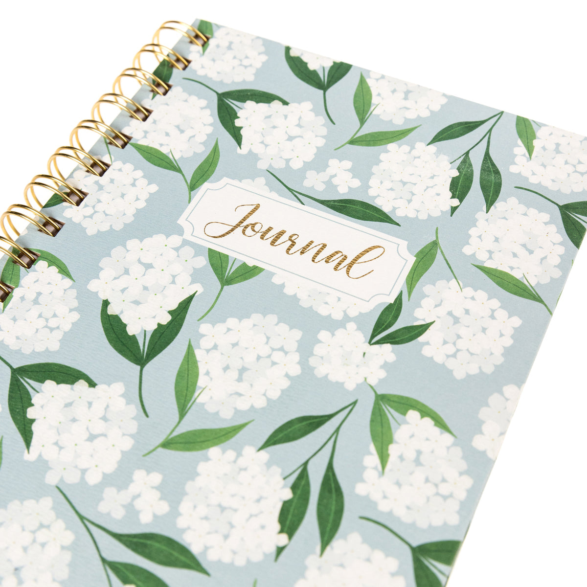 Hydrangeas Everyday Journal, A dusty blue spiral-bound journal covered in white hydrangea blooms and green leaves with a gold foil Journal label near the top.