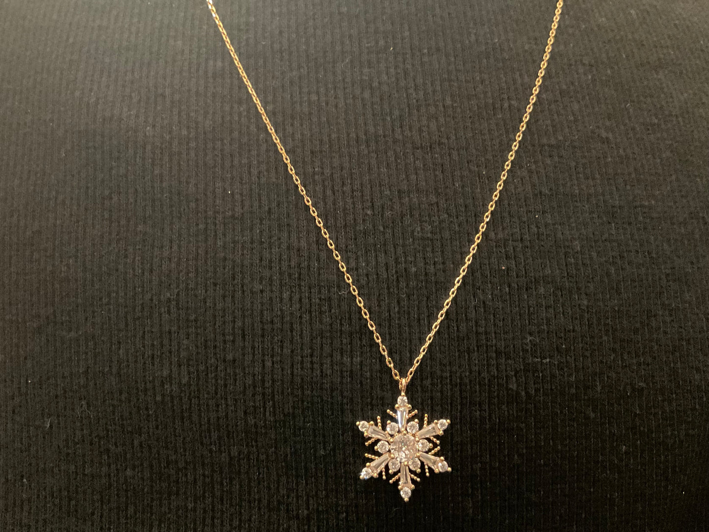 Copo de nieve de circonita dorada con cadena de oro.