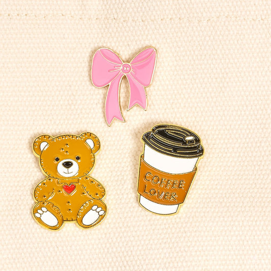Enamel Pin Pack, A boxed set of three gold enamel pins in the Latte Love design, a coffee cup, a teddy bear, and a pink bow.