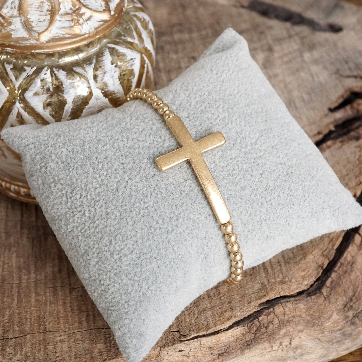 Pulsera elástica minimalista con cruz en tono dorado desgastado y cuentas de bola
