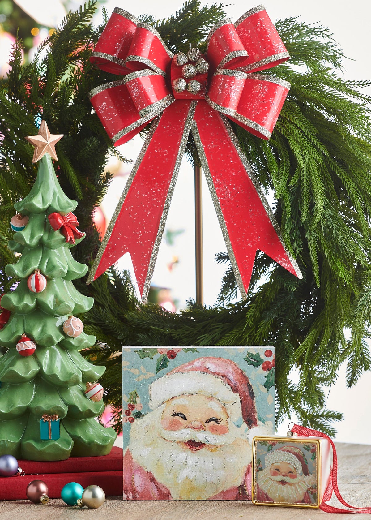 Decorated Ruffled Tree, A green resin tree with ruffled, tiered branches decorated with a red bow, pink and red ornaments, small teal wrapped gifts at the base, and a gold star on top.