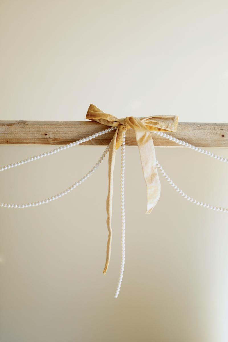 Gold Velvet Bow Garland with Faux Pearl Swag, A garland of velvet bows joined by gold rings with strands of faux pearls hanging between them.