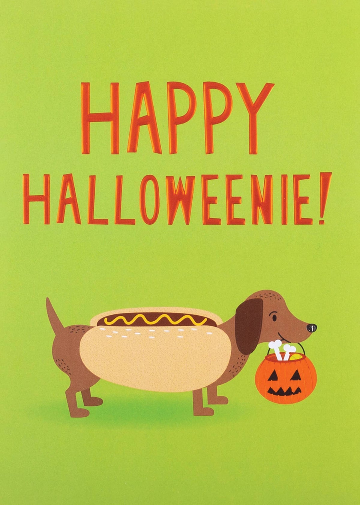 Happy Halloweenie Greeting Card, Front of a Halloween card on a green background with HAPPY HALLOWEENIE! in orange letters above a cartoon dachshund in a hot dog bun costume carrying a jack-o'-lantern pail of bones.