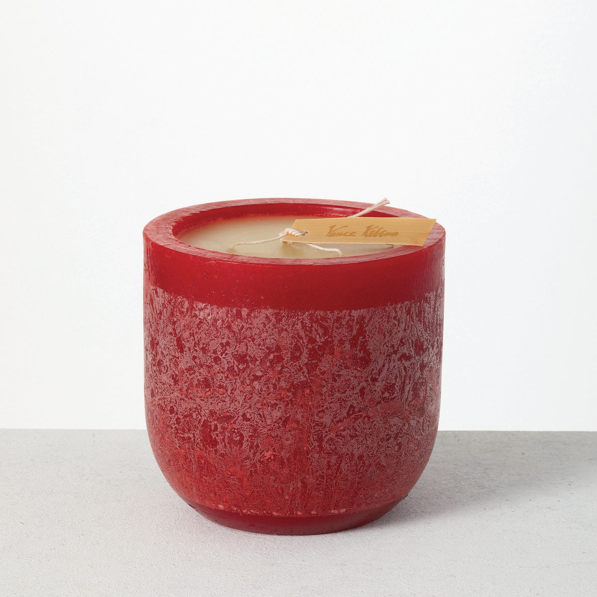 Timber Goblet Candle 6 x 6 Inch, A round, cup-shaped candle in golden amber wax with a mottled, bark-like surface, a wide cream wax top holding a looped wick, and a wooden tag reading Vance Kitira resting across the rim.