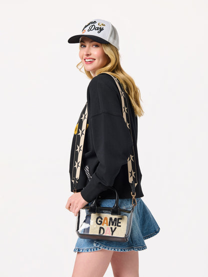 Spectator Clear Stadium Top Handle Cross-Body Bag, Black, A clear PU bag with black handles and gold hardware, with a long black and cream star-patterned strap hanging above it.