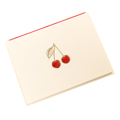 La Petite Presse Cherries Boxed Correspondence Notes, An ivory notecard with gold foil cherries filled in red glitter, paired with a cream envelope lined in bright red.