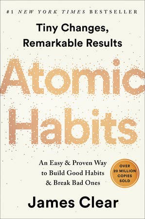 Libro Atomic Habits de James Clear sobre escritorio con café y cuaderno