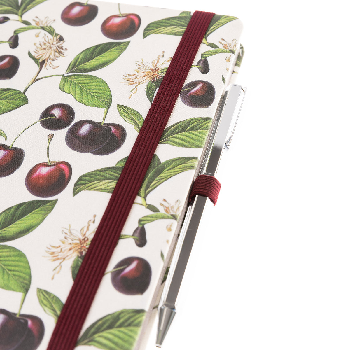 La Petite Presse Cerise Fabric-Bound Journal with Pen, An ivory fabric journal printed with botanical cherries and blossom sprigs, closed with a burgundy elastic band and a silver pen tucked into a loop.