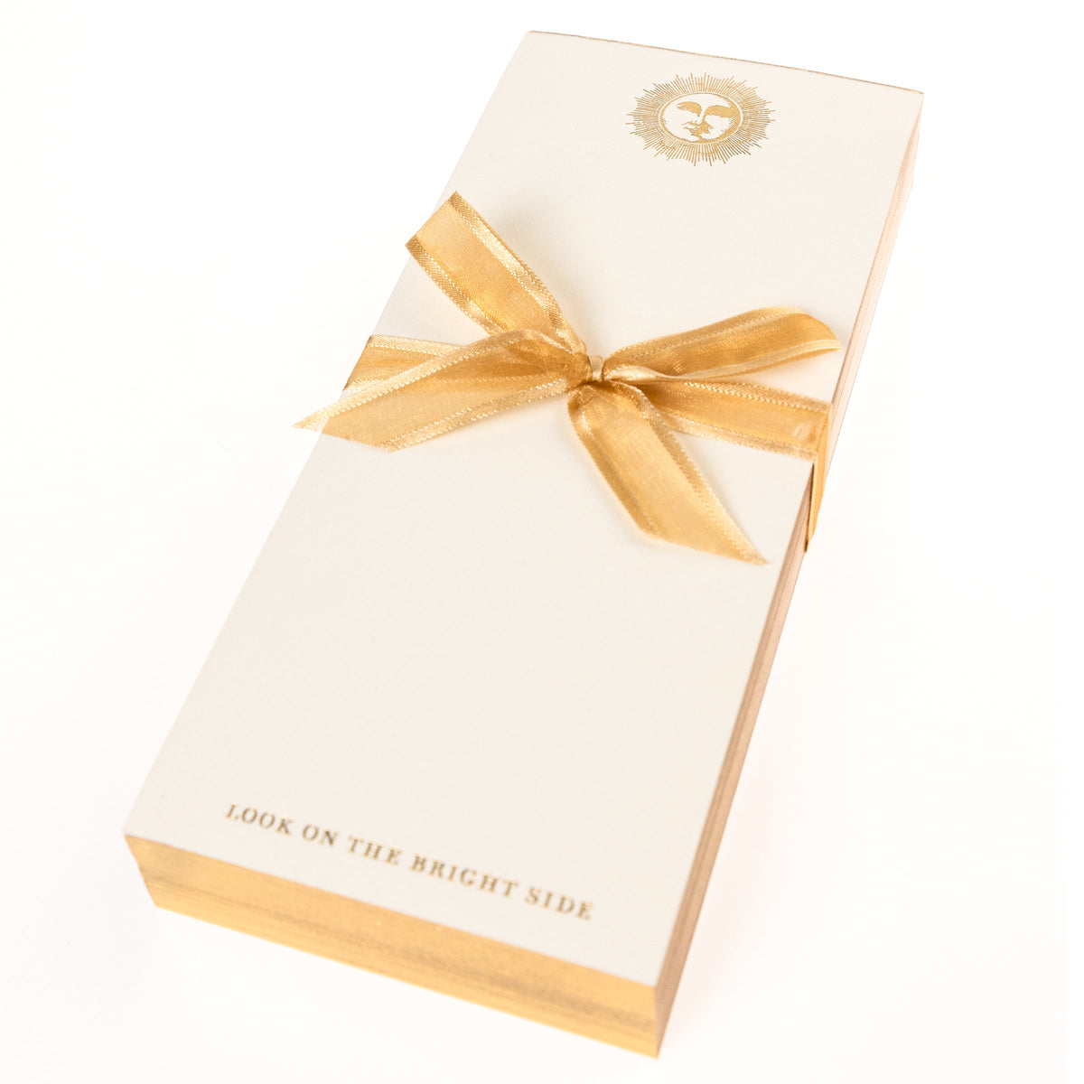 La Petite Presse Sun Gilded Desktop Notepad, A cream notepad with a gold foil sun and face design at the top and the words Look on the Bright Side stamped in gold at the bottom.