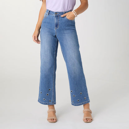Bambu Soft Heart Cut-Out Wide Leg Ankle Jeans, A woman in medium denim wide leg ankle jeans with heart cut-outs along the hems, a lavender top and braided sandals.