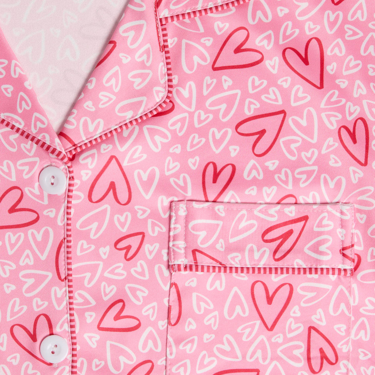 Dreamland Button Front Pajama Top, A smiling woman in a pink heart print button-front pajama top with piping, standing in matching pajama pants.