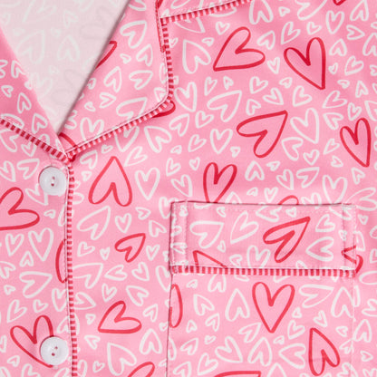 Dreamland Button Front Pajama Top, A smiling woman in a pink heart print button-front pajama top with piping, standing in matching pajama pants.
