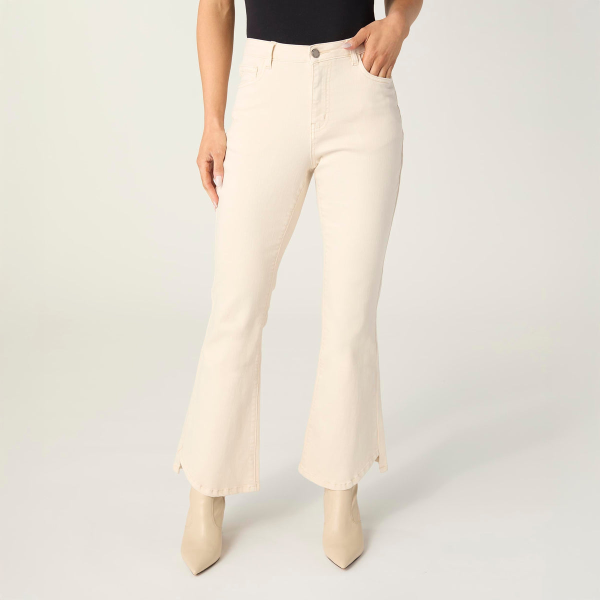 Willa Curved Hem Flare Pant, A woman's lower half in cream flare pants with a curved hem and pointed cream ankle boots.