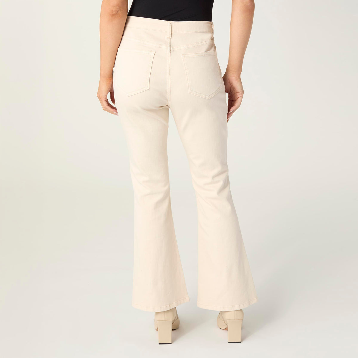 Willa Curved Hem Flare Pant, A woman's lower half in cream flare pants with a curved hem and pointed cream ankle boots.