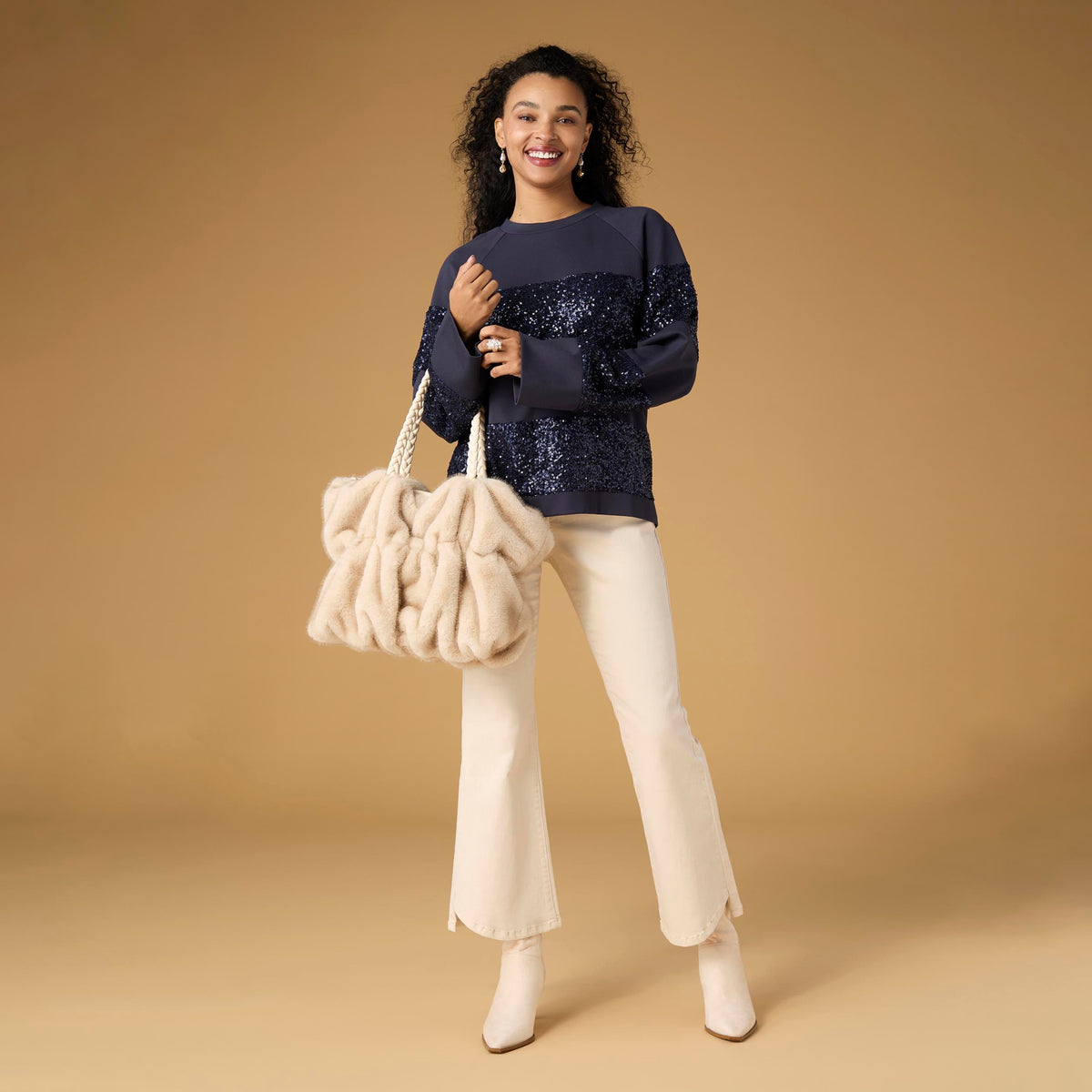 Willa Curved Hem Flare Pant, A woman's lower half in cream flare pants with a curved hem and pointed cream ankle boots.