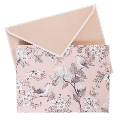 La Petite Presse Birds Boxed Correspondence Notes, A brown gift box open to a blush pink notecard printed with songbirds perched among magnolia blossoms, paired with a matching blush envelope.