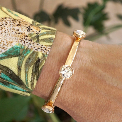 Brazalete de cristales transparentes brillantes en tono dorado o plateado.