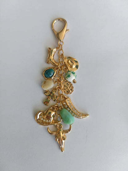 DIJE PARA BOLSO CON SOMBRERO VAQUERO Y BOTA CRUZADA DE PORCELANA OCCIDENTAL