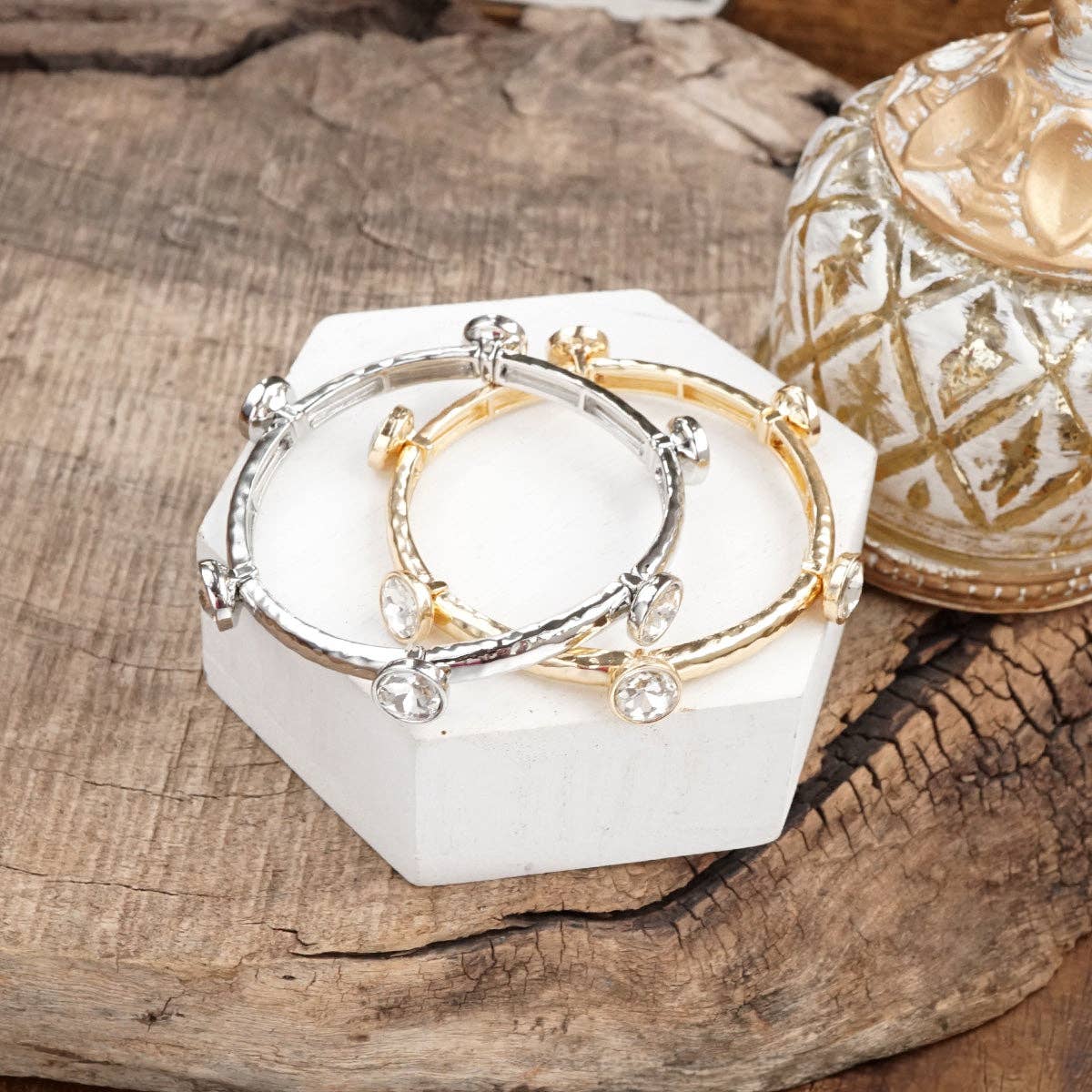 Brazalete de cristales transparentes brillantes en tono dorado o plateado.