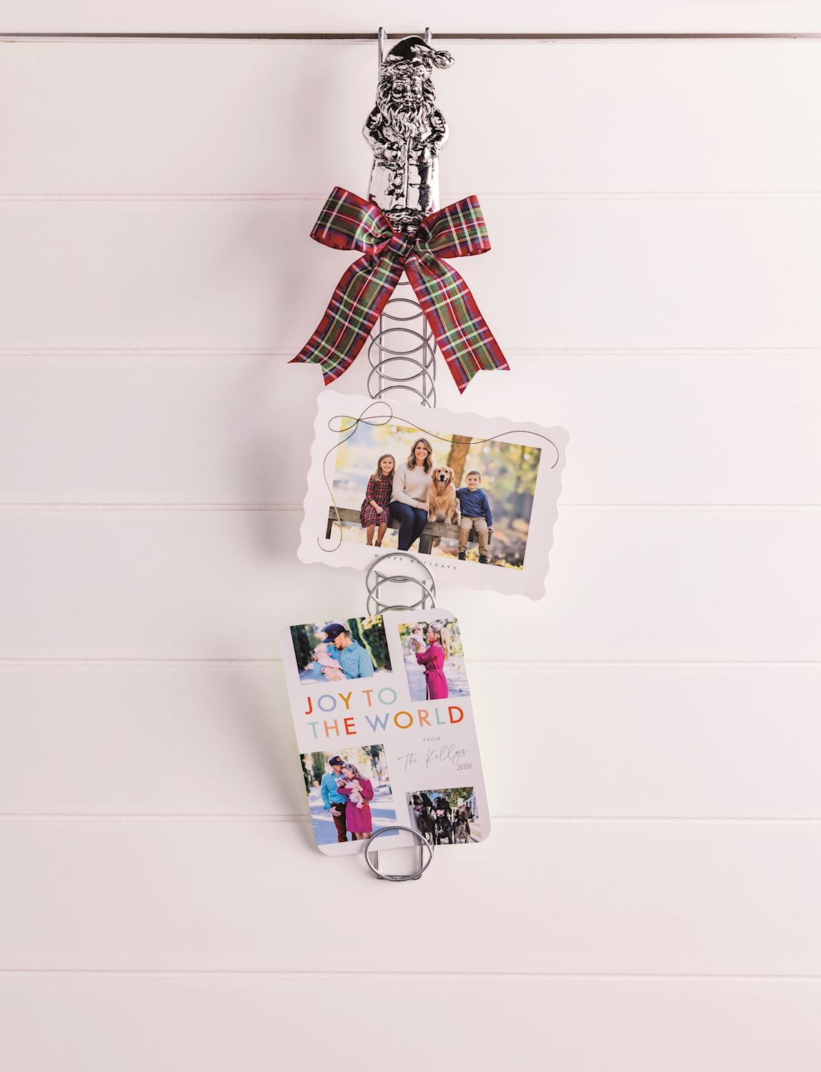 Santa Topper Metal Coil Christmas Card Holder, 23.5 Inch, A tall silver-tone metal coil card holder with a cast aluminum Santa figure at the top and a holiday photo card tucked between the rings.