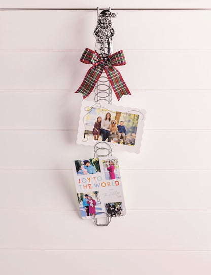 Santa Topper Metal Coil Christmas Card Holder, 23.5 Inch, A tall silver-tone metal coil card holder with a cast aluminum Santa figure at the top and a holiday photo card tucked between the rings.