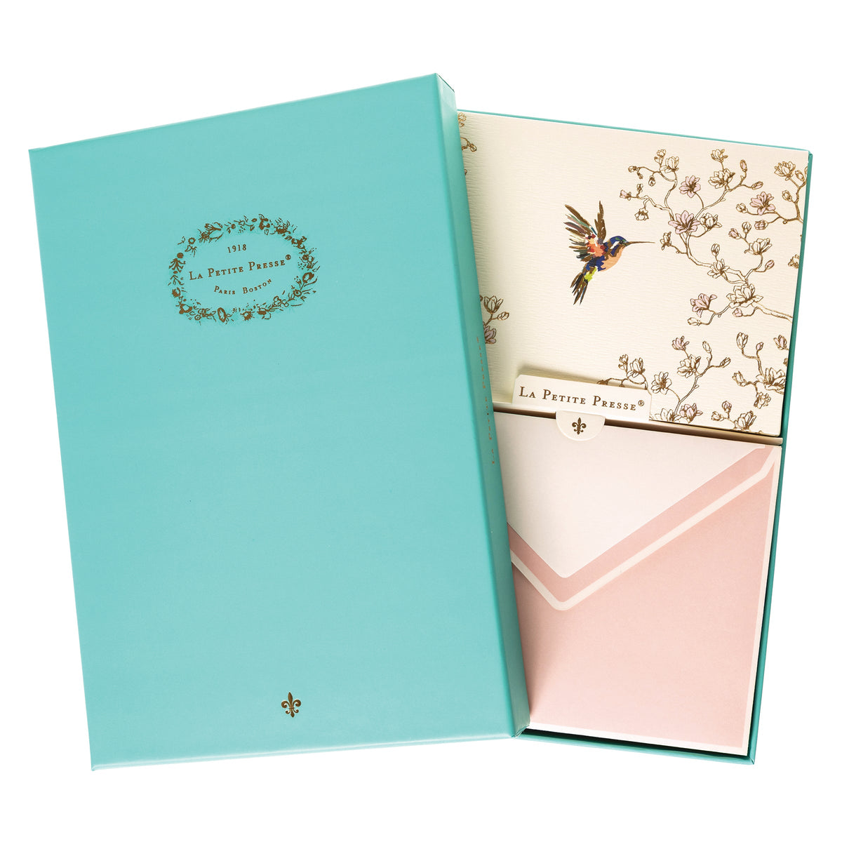 La Petite Presse Hummingbird Boxed Correspondence Notes, A cream notecard with a colorful hummingbird and gold magnolia branch line art, paired with a blush pink lined envelope.