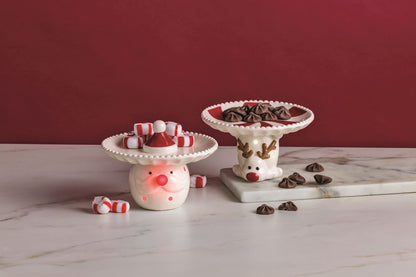 Santa Light-Up Candy Pedestal Dish, 5.5 Inch, A white ceramic pedestal dish with a beaded rim and a small red Santa hat at its center, resting on a base shaped like a Santa face with a red nose and molded moustache.