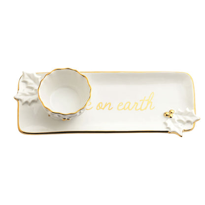 Gold Holly Tray and Tidbit Bowl Set, A long white stoneware tray lettered peace on earth in gold with sculpted holly leaves and gold berries, shown beside a small scalloped bowl with a gold rim.