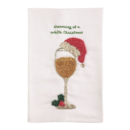 Dreaming of a White Christmas Beaded Wine Glass Towel, A white cotton towel with green embroidered script reading dreaming of a white Christmas above a beaded wine glass wearing a red santa hat, with holly at its base.