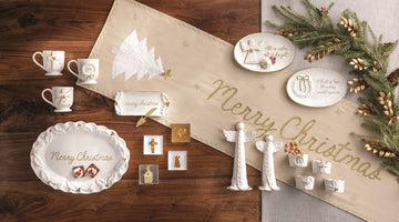 Gold Holly Butter Dish and Spreader Set, A white stoneware butter dish with sculpted holly leaves at each end, gold berries, a gold rim and merry christmas in gold script, shown with a gold spreader with a Christmas tree handle.