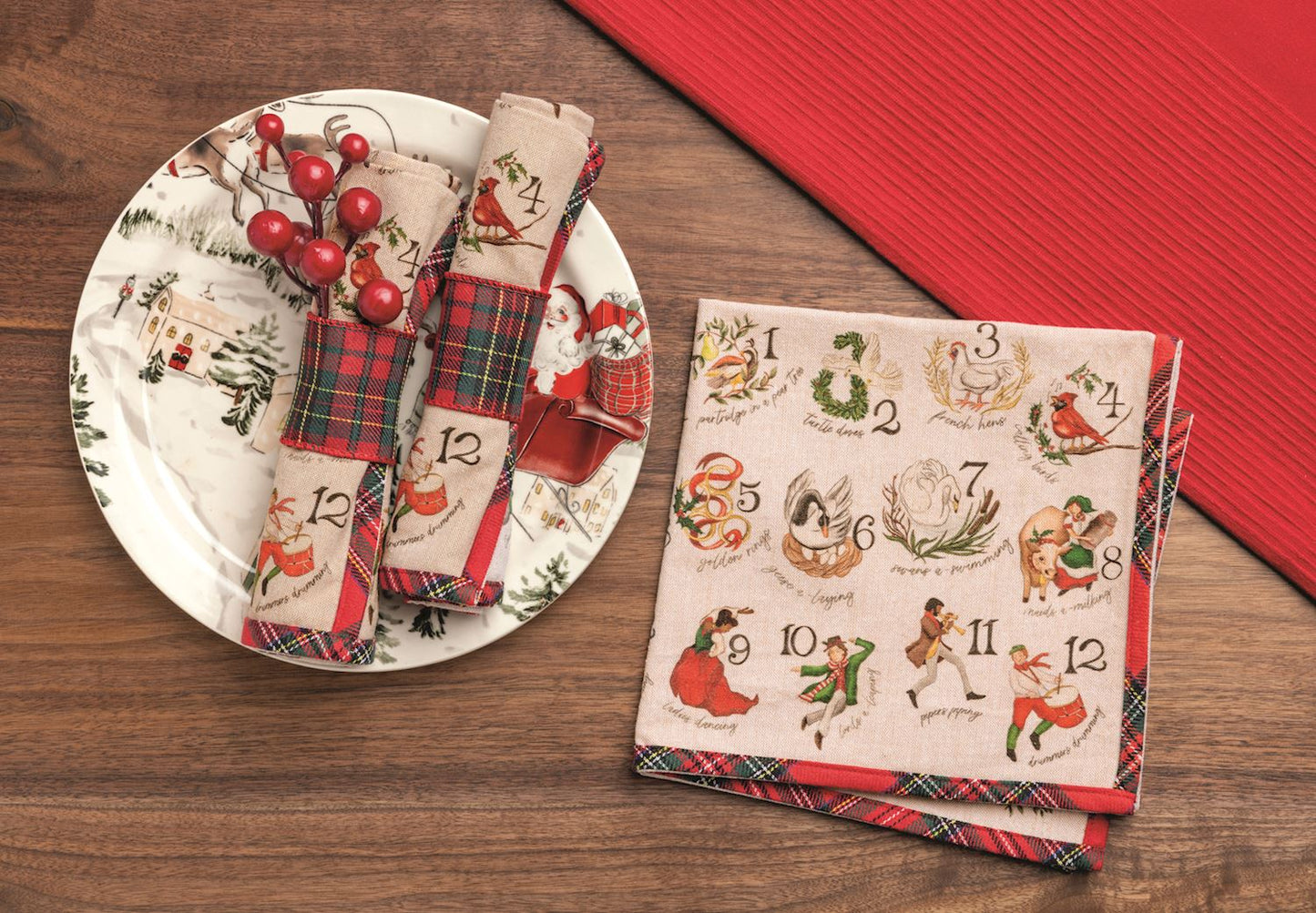 12 Days of Christmas Cotton Napkins, Set of 4, Folded oatmeal colored cotton napkins printed with numbered 12 Days of Christmas illustrations and edged in red tartan plaid, banded with a kraft tag.