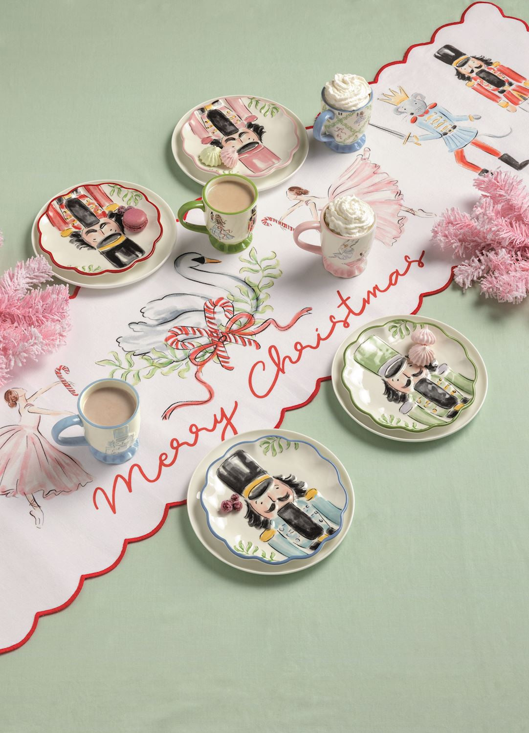 Nutcracker Merry Christmas Table Runner, Long white table runner with a red scalloped edge, painted with nutcracker soldiers, crowned mice holding swords, pink ballerinas and a swan in a wreath, and Merry Christmas in red script.