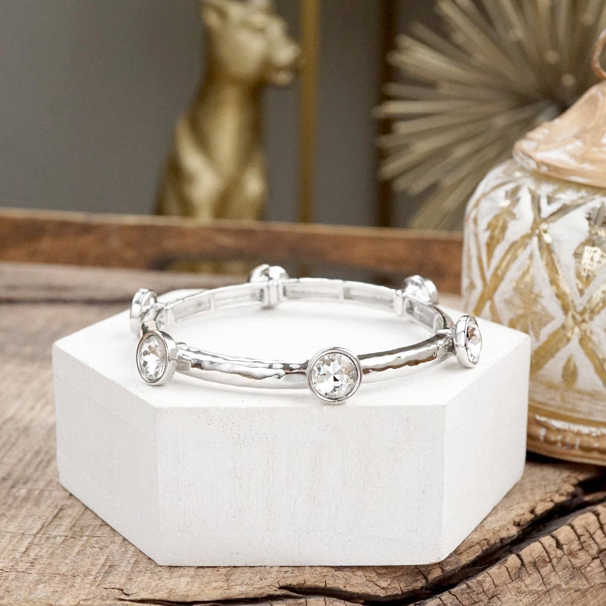 Brazalete de cristales transparentes brillantes en tono dorado o plateado.