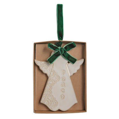 Peace Angel Stoneware Ornament with Velvet Ribbon, A cream ceramic angel ornament with pressed lace texture and the word Peace, tied with a green velvet ribbon and lying in a kraft gift box.