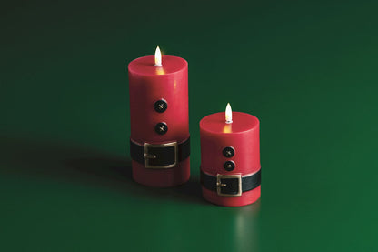 Santa Suit Flameless LED Pillar Candle, A red wax pillar candle painted as a Santa suit with two black buttons and a black belt with a gold buckle, wrapped in cellophane tied with twine.