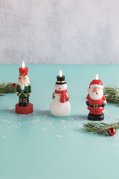 Snowman Figural Flameless Candle, A white snowman shaped wax candle with a black top hat, red scarf, carrot nose and coal buttons, wrapped in clear cellophane tied with red and white twine.