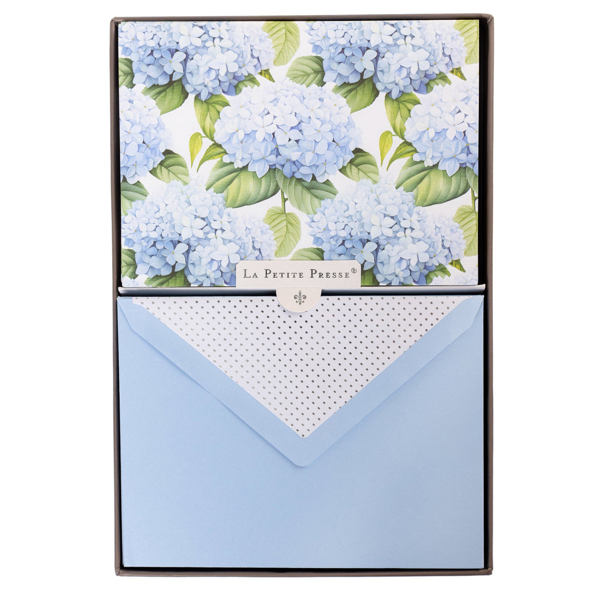 La Petite Presse Hortensia Boxed Correspondence Notes, A brown gift box open to a white notecard printed with powder blue hydrangea blooms, paired with a matching blue envelope.
