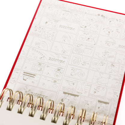 Peanuts Fabric-Bound Notepad, A red fabric-bound notepad with Snoopy typing at his typewriter in gold foil on the cover and gold gilded page edges.