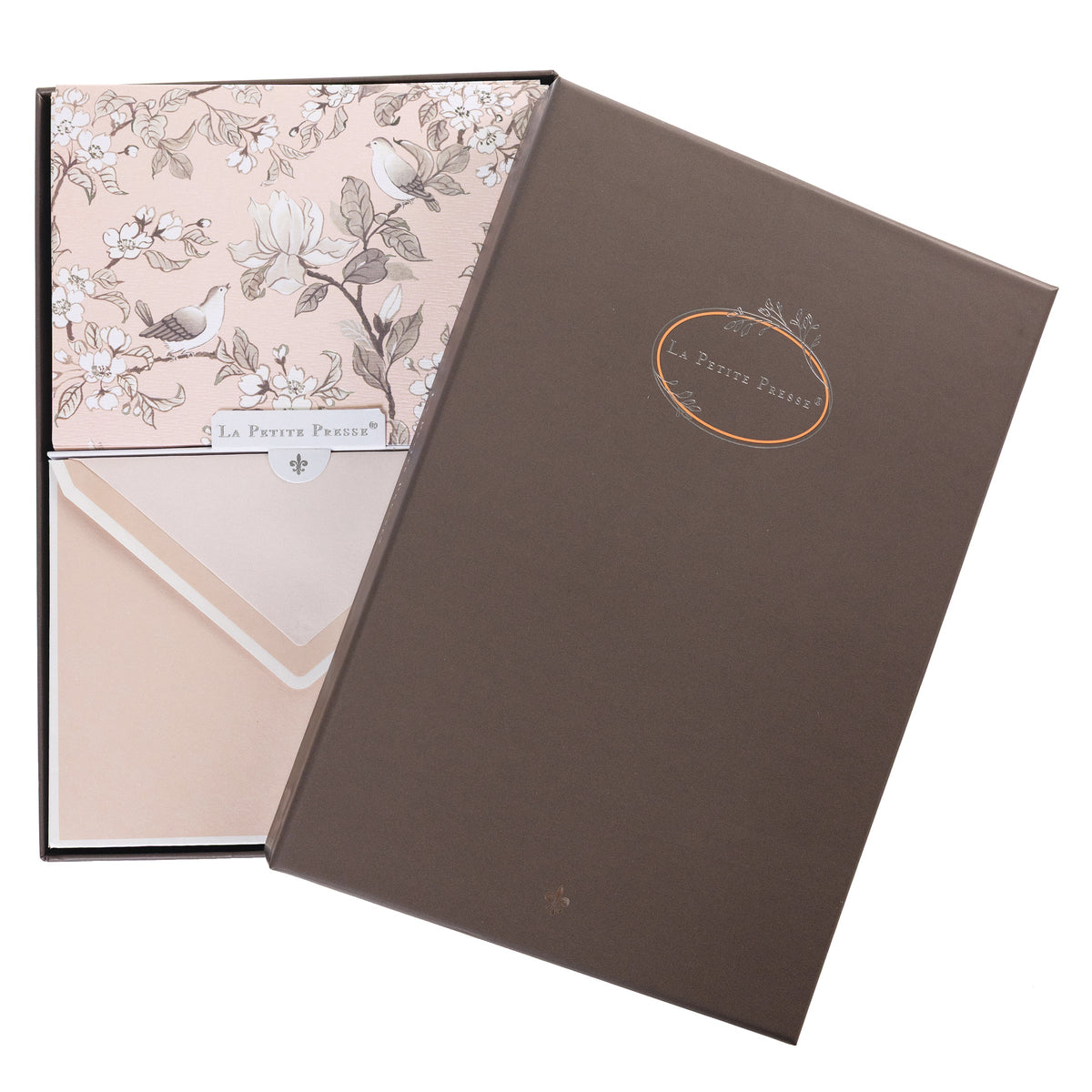 La Petite Presse Birds Boxed Correspondence Notes, A brown gift box open to a blush pink notecard printed with songbirds perched among magnolia blossoms, paired with a matching blush envelope.