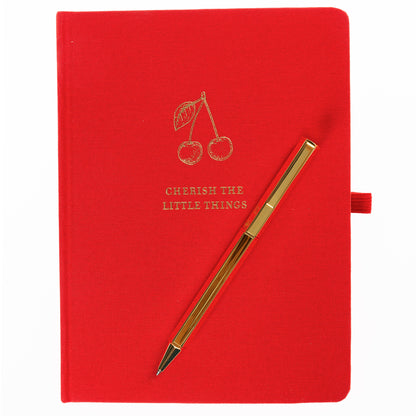 La Petite Presse Cherry Fabric-Bound Journal with Pen, A cherry red fabric journal with gold foil cherries and the words Cherish the Little Things on the cover, paired with a gold twist pen.