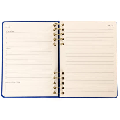Cobalt Blue Fabric-Bound Task Journal, A cobalt blue fabric-covered task journal with gold twin wire spirals and two navy ribbon bookmark tabs, closed with an elastic band.