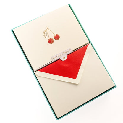 La Petite Presse Cherries Boxed Correspondence Notes, An ivory notecard with gold foil cherries filled in red glitter, paired with a cream envelope lined in bright red.
