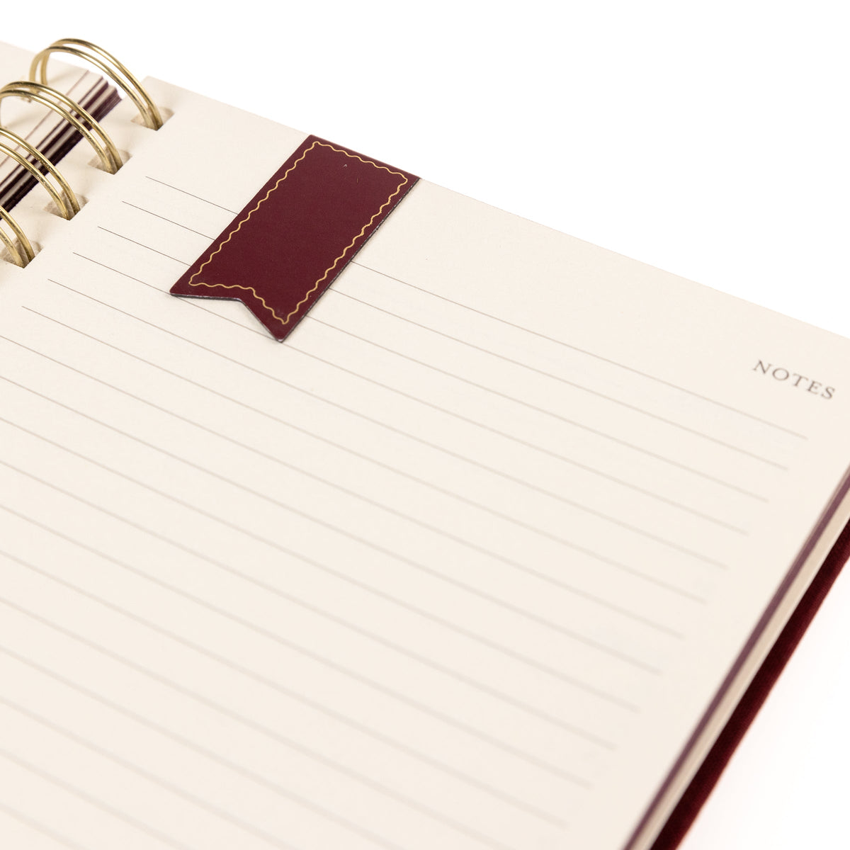 Burgundy Fabric-Bound Task Journal, A burgundy fabric-covered task journal with gold twin wire spirals and two maroon ribbon bookmark tabs, closed with an elastic band.