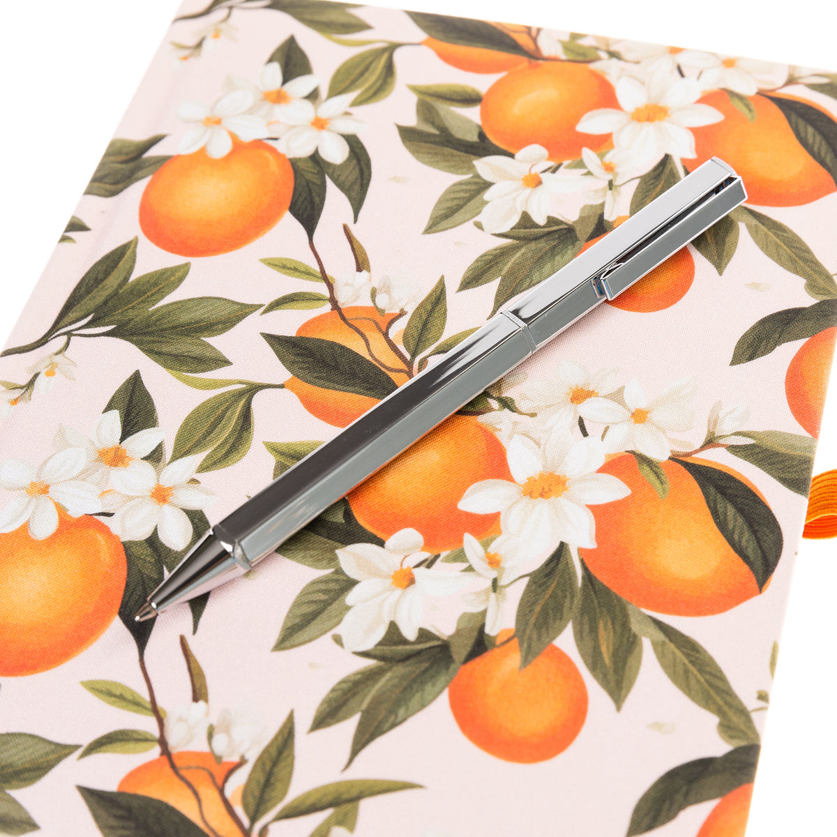 La Petite Presse L'Orange Fabric-Bound Journal with Pen, An orange grove fabric journal, closed with an orange elastic band and a silver pen tucked into a loop.