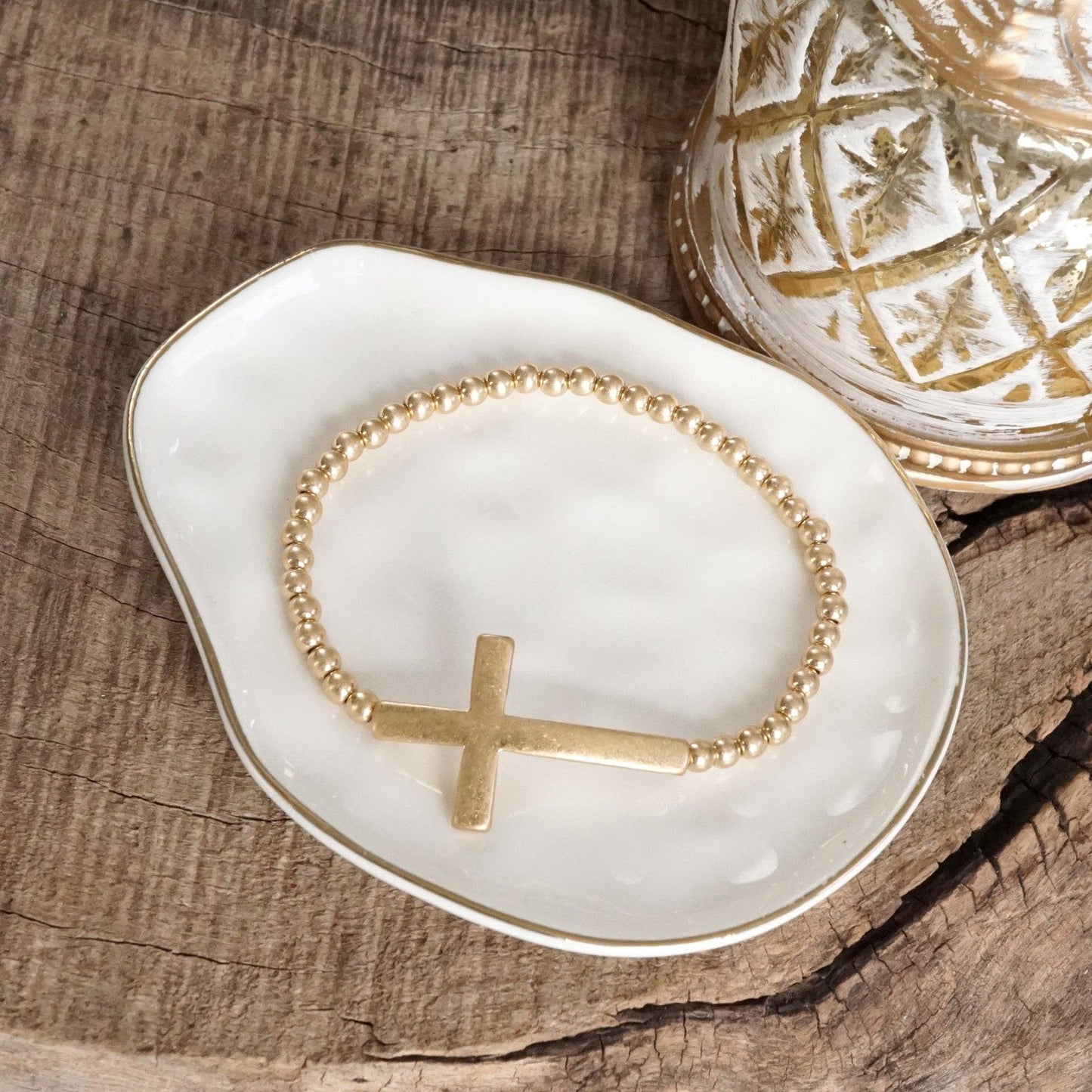 Pulsera elástica minimalista con cruz en tono dorado desgastado y cuentas de bola