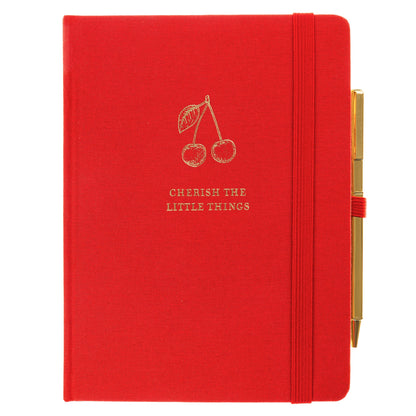 La Petite Presse Cherry Fabric-Bound Journal with Pen, A cherry red fabric journal with gold foil cherries and the words Cherish the Little Things on the cover, paired with a gold twist pen.