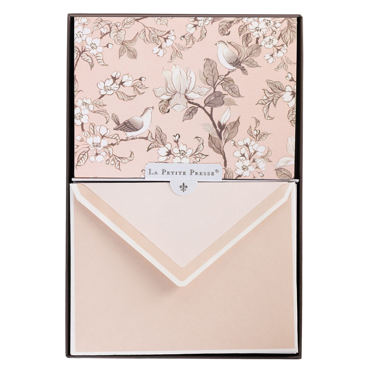 La Petite Presse Birds Boxed Correspondence Notes, A brown gift box open to a blush pink notecard printed with songbirds perched among magnolia blossoms, paired with a matching blush envelope.
