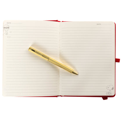Peanuts Fabric-Bound Journal with Pen, A red fabric journal with a gold foil Snoopy illustration and the words happy notes, paired with a gold pen tucked into a loop along the spine.