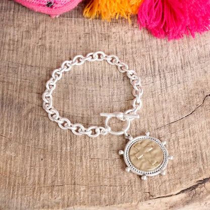 Pulsera de cadena con monedas cruzadas y cierre de palanca en tono plateado o dorado